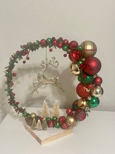 a christmas wreath with ornaments on it and a deer ornament in the middle