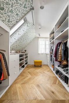 a walk - in closet with white shelves and wooden flooring, built into the wall