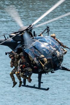 two men are jumping off the back of a helicopter into the water while another man is in mid air