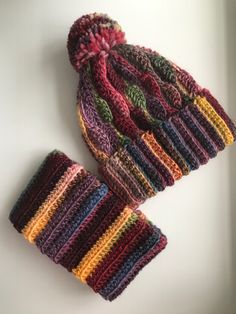 two multicolored knitted beanies sitting on top of a white table next to each other