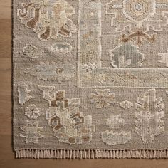 an old rug is on the floor with wood floors in the background and a wooden table top