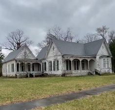 an old white house sitting on the side of a road