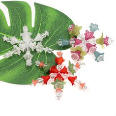 a group of flowers sitting on top of a green leaf next to crystal stones and beads