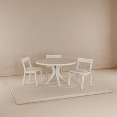 a white table and two chairs sitting on top of a rug in front of a wall