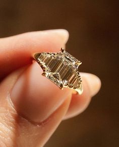 a woman's hand holding an engagement ring with two diamonds on the top and bottom