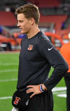 a man standing on top of a field with his hands on his hips while wearing a black shirt