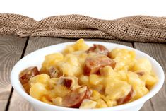 a white bowl filled with macaroni and cheese on top of a wooden table