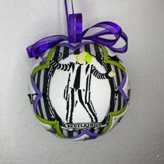 an ornament hanging on the wall with a purple ribbon