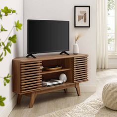 a flat screen tv sitting on top of a wooden entertainment center in a living room