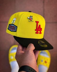 a person holding up a yellow and black hat with the los angeles angels on it