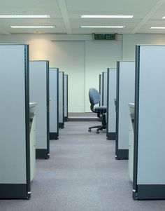 an empty office cubicle with chairs and desks