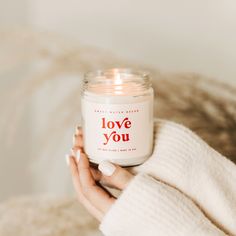 a woman holding a candle in her hand with the words love you written on it