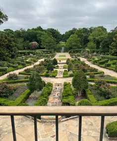 a view of a formal garden from the top of a balcony in front of trees and bushes