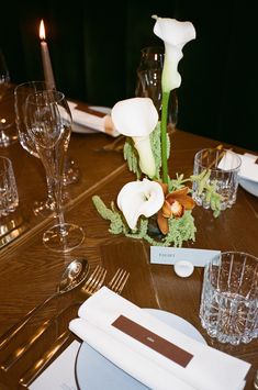 the table is set with white flowers and place settings