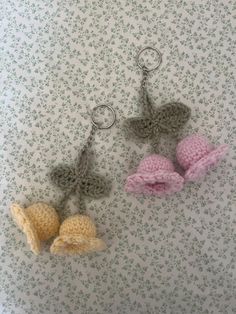 two crocheted keychains are hanging from hooks on a floral wallpaper