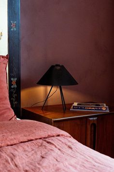 a bed with pink linens and a black lamp on the nightstand next to it