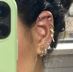 a close up of a person's ear with some piercings on it and a cell phone in the background