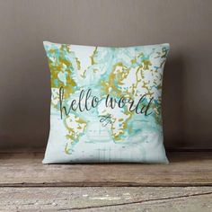 a pillow with the words hello world printed on it sitting on a wooden table in front of a wall