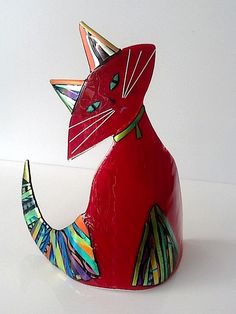 a red ceramic cat sitting on top of a white table