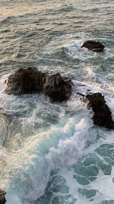 the ocean waves are crashing on the rocks