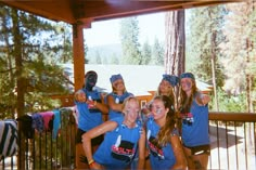 a group of young women standing next to each other on top of a wooden deck