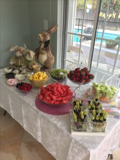 a table topped with lots of different types of fruit and veggies next to a window