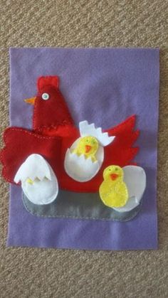 a piece of felt with an image of a chicken and two chicks on it sitting on the ground