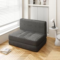 a gray couch sitting on top of a wooden floor next to a radiator