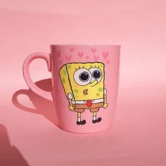 a pink coffee cup with a cartoon character on the side and hearts in the background