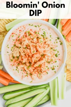 a white bowl filled with dip surrounded by celery, carrots and crackers