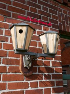 two birdhouses are attached to the side of a brick building with red lettering on it