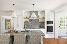 a kitchen with marble counter tops and white cabinets, along with an island in the middle