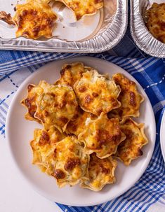 some food is sitting on a white plate and blue checkered table cloth with silver trays