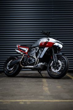 a silver and red motorcycle parked in front of a garage door with a black background