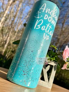 a blue and white water bottle sitting on top of a wooden table next to flowers