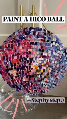 a colorful disco ball sitting on top of a glass stand with pink and blue tiles