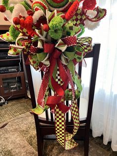 a christmas tree decorated with red, green and white ribbons on a chair in front of a window