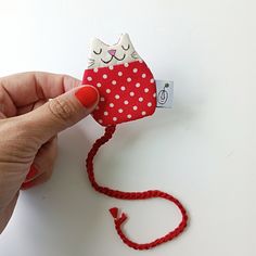 a hand holding a small red and white cat decoration