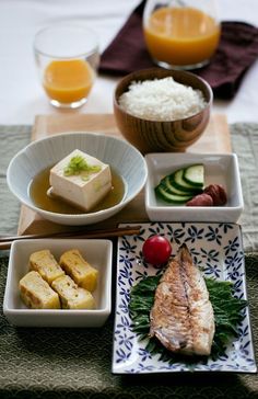 there are many different dishes on the table with rice and fruit in bowls next to each other