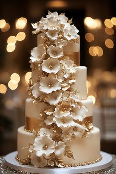 a white and gold wedding cake with flowers on it