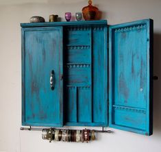 an old blue cabinet is hanging on the wall