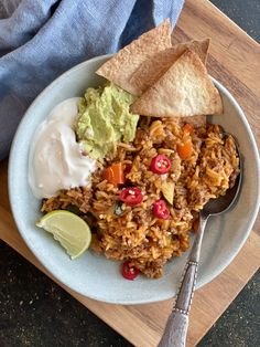 a white plate topped with rice, guacamole and tortilla chips