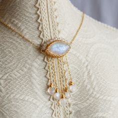 Crafted from a beautiful Marquise Rainbow Moonstone, this pendant has been artfully designed with a delicate cable-chain, a secure spring clasp and extension, and is adorned with a halo of white Cubic and five ethereal Moonstone teardrop tassels in 14K gold filled. In strong light, the main stone glimmers like the moon itself! The pictures do not adequately convey the exclusive beauty of this one-of-a-kind piece from Artisan Made. An effortless yet sophisticated accessory, it's perfect for eleva White Moonstone Jewelry With Adjustable Chain, Bohemian Moonstone Crystal Necklace, Witchy Whimsical, Moonstone Amulet Necklace With Gemstone, Luxury Mystical Moonstone Necklace, Iridescent Moonstone Gemstone Necklaces, Ethereal Jewelry, Rainbow Moonstone Crystal, Whimsical Jewelry