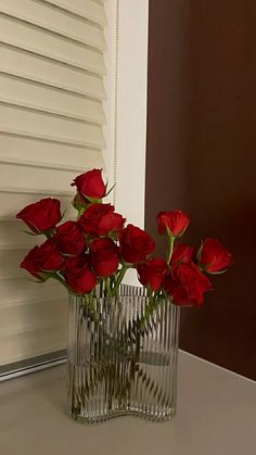 some red roses are in a clear vase