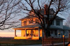 a large white house sitting on the side of a road next to a tall tree