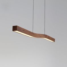 a wooden light fixture hanging from the ceiling with two strings attached to it, in front of a gray background