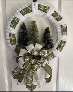 a christmas wreath hanging on the front door with snowflakes and pine trees in it