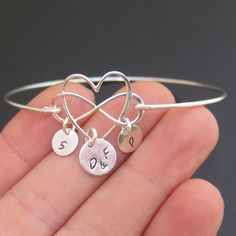 "Family Infinity Heart Bracelet - Personalized Mother's Day Gift Jewelry Choose infinity heart charm in sterling silver or 14k gold filled to be transformed into a personalized family bracelet with the initials of family members and bangle band in matching finish. Please mention initials in notes to seller during checkout. The first initial charm dangles from the heart in the middle. I can stamp parent's or couple's initials, mom's initial or guardian's initials, or grandparent's initials. I can Sterling Silver Name Bracelet With Heart Charm For Gift, Heart Charm Bangle For Anniversary, Anniversary Heart Charm Bangle Jewelry, Anniversary Bangle With Heart Charm, Nickel-free Heart Jewelry For Personalized Gift, Silver Infinity Jewelry For Anniversary, Heart-shaped Cadmium-free Jewelry For Gifts, Hypoallergenic Double Heart Jewelry, Adjustable Hallmark Jewelry For Gifts