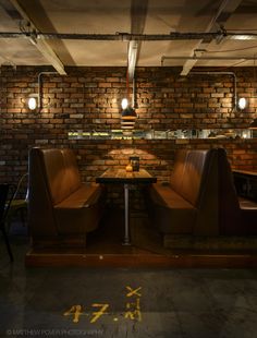 two brown chairs sitting next to each other in front of a table with a lamp on it