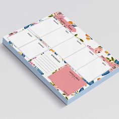 a pink and blue planner with floral designs on it, sitting on top of a gray surface